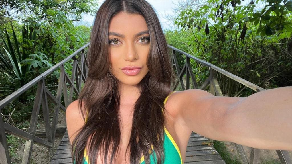Victoria en un puente de madera con top verde y amarillo halter, vegetación al fondo.